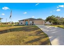 One-story home with teal door, driveway and American flag at 6560 Sw 129Th St, Ocala, FL 34473