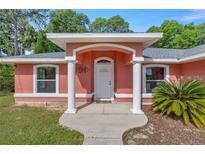 Inviting coral exterior with a welcoming front porch and landscaping at 3792 Sw 152Nd Ct, Ocala, FL 34481