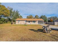 Tan house with screened porch, large yard, and long driveway at 9255 Se 109Th Ln, Belleview, FL 34420