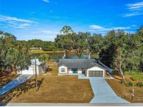 Aerial view of single-story home with lake access, detached garage, and spacious driveway at 17757 Se 28Th Ln, Silver Springs, FL 34488