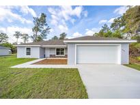 Newly constructed home with gray exterior, white garage door, and landscaping at 22160 Sw Neptune Blvd, Dunnellon, FL 34431