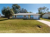 Light blue house with a white garage door and well-manicured lawn at 24 Banyan Dr, Ocala, FL 34472