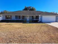 Cute ranch home with a blue exterior, white garage door, and landscaping at 17 Pecan Crse Dr, Ocala, FL 34472