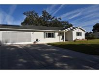 Single-story home with attached garage and well-maintained lawn at 9669 Se 174Th Place Rd, Summerfield, FL 34491