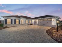 Two-story house with a three-car garage, paver driveway, and landscaping at 9739 Sw 79Th Lane Rd, Ocala, FL 34481