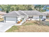 White single-story house with gray roof, attached garage, and landscaped front yard at 58 Teak Loop, Ocala, FL 34472