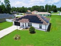 Single-story house with solar panels, driveway, and grassy yard at 7721 Sw 130Th Ln, Ocala, FL 34473