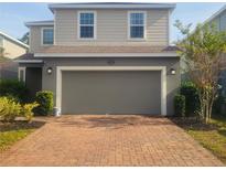 Two-story house with gray siding, brick driveway, and a two-car garage at 1609 Chelsea Manor Cir, Deland, FL 32724