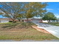 Pink single-story house with a two-car garage and mature landscaping at 8478 Sw 60Th Ct, Ocala, FL 34476