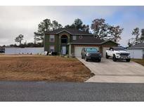 Two-story house with a large driveway, two-car garage, and fenced yard at 4030 Sw 132Nd Ln, Ocala, FL 34473