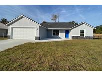 New construction home with gray exterior, white garage door, and blue front door at 4063 Se 136 Th Pl, Summerfield, FL 34491