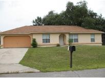 Tan one-story house with attached garage and a small lawn at 14652 Sw 22Nd Court Rd, Ocala, FL 34473