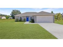 Newly built home with a gray exterior, blue door, and attached garage at 115 Guava Place Dr, Ocklawaha, FL 32179