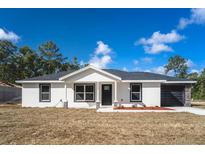 Newly constructed home with a white exterior, black garage door, and stone accents at 16919 Sw 27Th Ave, Ocala, FL 34473