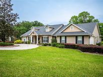 Single-story home with a landscaped lawn, driveway, and attached garage at 1945 Sw 40Th Pl, Ocala, FL 34471