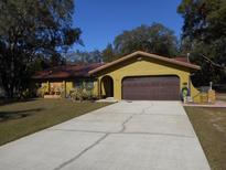 Ranch style home with a brown garage door and a long driveway at 611 Sw Shorewood Dr, Dunnellon, FL 34431