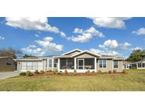 Tan house with screened porch, attached garage, and well-manicured lawn at 10804 Sw 81St Court Rd, Ocala, FL 34481