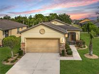 Tan house with a two-car garage and landscaped lawn at 7732 Sw 94Th Cir, Ocala, FL 34481