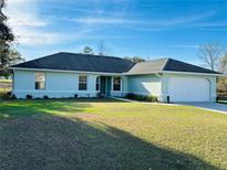 Single-story house with a green lawn and a white garage door at 15025 Sw 24Th Cir, Ocala, FL 34473