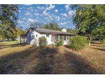 White house exterior with screened porch, surrounded by trees and yard at 11360 Se 188Th Ave, Ocklawaha, FL 32179