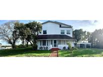 Two-story white house with a large front yard and mature trees at 34 Pine Rd, Babson Park, FL 33827