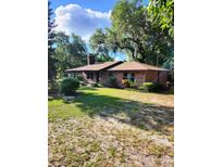 Brick ranch house with a spacious lawn and mature trees at 4450 Old Berkley Rd, Auburndale, FL 33823