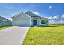 Newly constructed home with a light green exterior, two-car garage, and a well-manicured lawn at 4073 Tullamore Ln, Auburndale, FL 33823