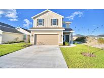 Two story house with tan siding, a two car garage, and landscaping at 1472 Leamington Ln, Winter Haven, FL 33884