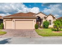Beige house with brown roof, two-car garage, and landscaped yard at 4568 Back Nine Dr, Winter Haven, FL 33884