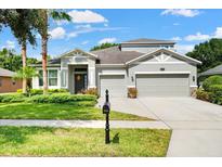 Two-story house with a three-car garage and manicured lawn at 124 Magneta Loop, Auburndale, FL 33823