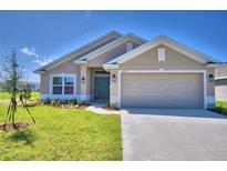 Tan house with a two-car garage and landscaping at 1249 Tagliamento Ln, Haines City, FL 33844