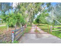 Long driveway leading to a property with a rustic wooden gate at 1955 W Lake Hamilton Dr, Winter Haven, FL 33881