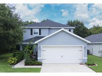 Two-story house with gray siding, white garage door, and landscaping at 997 Pearly Ridge Ln, Lakeland, FL 33809