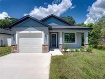 Newly constructed home featuring gray siding, a white garage door, and a stone accent at 213 Cordova Rd, Auburndale, FL 33823