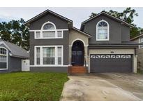 Two-story house with gray siding, a double garage, and a brick walkway at 5219 Mystic Point Ct, Orlando, FL 32812
