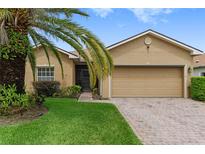 Tan house with a palm tree, brick driveway and two car garage at 4432 Waterford Dr, Lake Wales, FL 33859