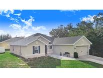 Tan house with a two-car garage and green lawn at 230 Grouper Ct, Poinciana, FL 34759