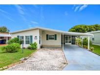 Single-wide manufactured home with covered carport and landscaped yard at 6762 Brentwood Ne Dr, Winter Haven, FL 33881