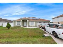 House exterior featuring a green facade, solar panels, and a two-car driveway at 1028 Dampierre Ct, Kissimmee, FL 34759