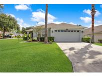 Single-story home with gray garage door, lush lawn, and palm trees at 1591 Forest Hills Ln, Haines City, FL 33844