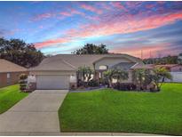 Beautiful single-story home with a well-manicured lawn and a stunning sunset in the background at 5808 Driftwood Dr, Winter Haven, FL 33884