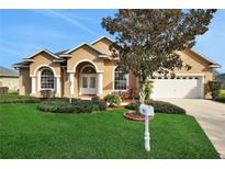 One-story house with tan exterior, arched entryway, and landscaped lawn at 231 Terranova Blvd, Winter Haven, FL 33884