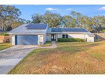 House exterior featuring a metal roof, solar panels, and a landscaped lawn at 4210 Old Colony Rd, Mulberry, FL 33860