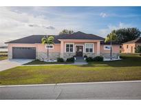 One-story home with peach siding, dark brown garage door, and landscaping at 8243 Alturas Rd, Bartow, FL 33830