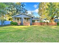 Gray house with wooden porch and brick wall, spacious lawn at 2036 Lake Ariana Blvd, Auburndale, FL 33823