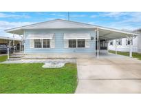 Light blue mobile home with carport and landscaped lawn at 6308 Bayberry Ne Blvd, Winter Haven, FL 33881