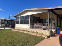 Mobile home exterior with covered porch, landscaping, and a pink flamingo decoration at 6447 Hollyberry Ne Ln, Winter Haven, FL 33881