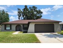 House exterior, brown roof, attached garage, and lawn at 609 Estrada Ln, Kissimmee, FL 34758