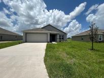 Newly constructed home with a 2-car garage and a well-manicured lawn at 1049 Bergamot Dr, Bartow, FL 33830