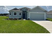 One-story house with gray siding, two-car garage, and landscaped lawn at 1218 Navel Rd, Bartow, FL 33830